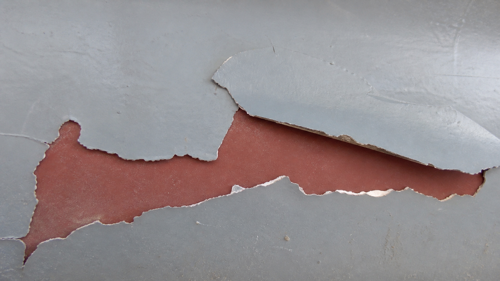 Photorealistic illustrative reference showing intercoat delamination on a protective coating system