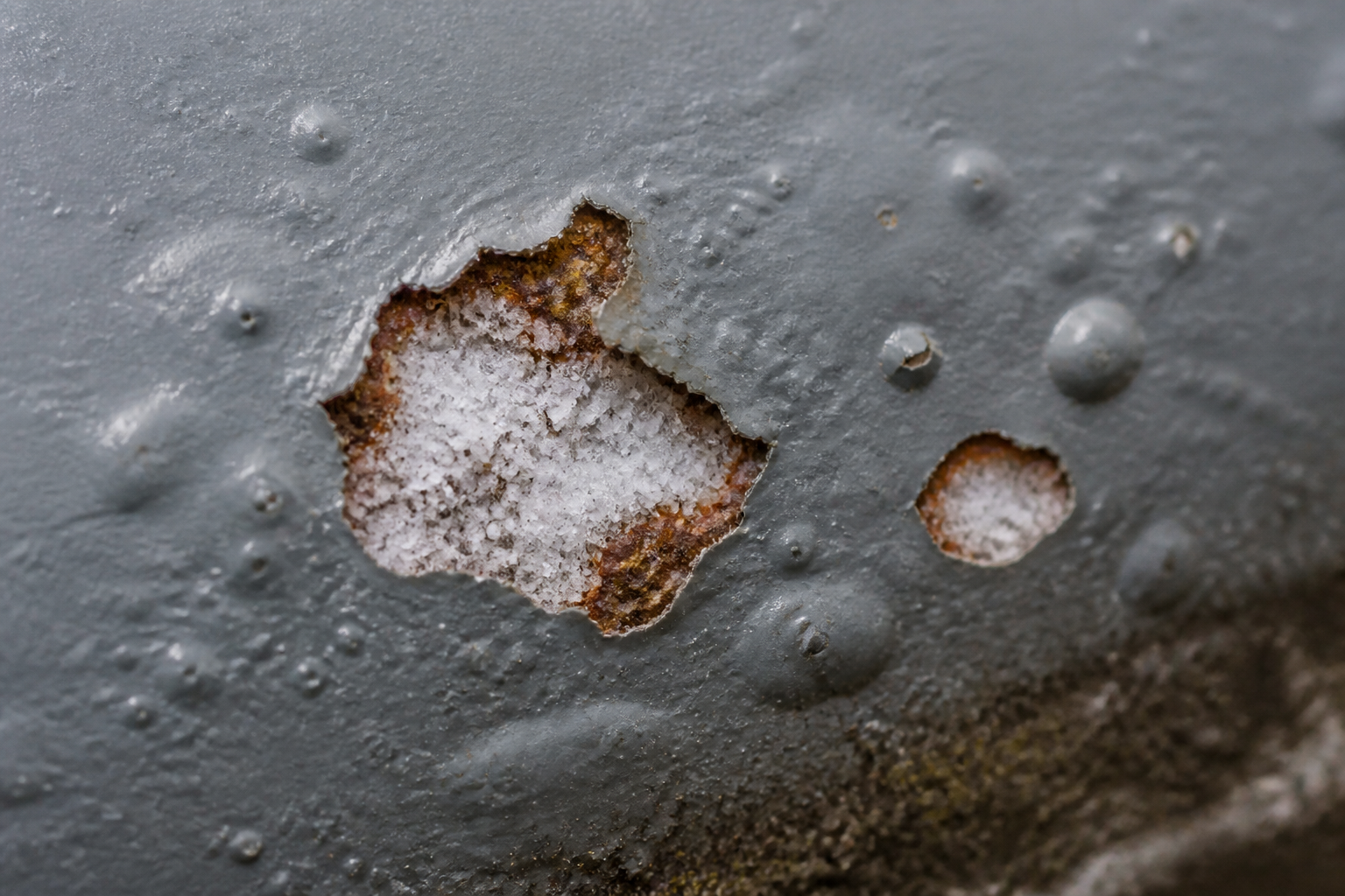 Photorealistic illustrative reference showing salt contamination on a protective coating system